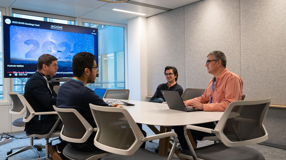 Meeting room with 4 people and a videoconference system with screen